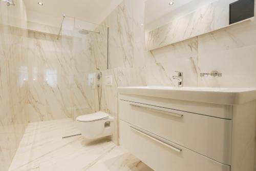 a white bathroom with a sink and a toilet at Beachfront luxury apartment in Budva