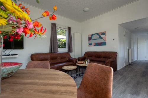 a living room with a couch and a table and chairs at Recreatiepark Jachthaven De Veerstal Lathum - Luxe Chalet in Lathum