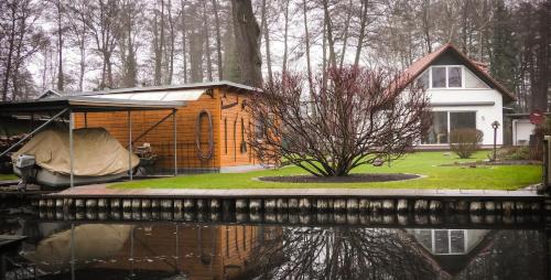 a small house with a tent next to a body of water at Ferienhaus direkt an der Spree mit Whirlpool und Sauna in Berlin