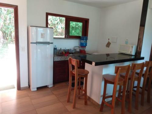 a kitchen with a counter and a refrigerator and chairs at Guaramiranga Monte Verde in Guaramiranga