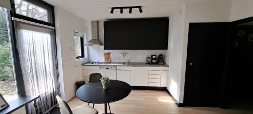 オッテルローにあるKnusse Bungalow Otterlo Veluweの小さなキッチン(テーブル、黒いキャビネット付)