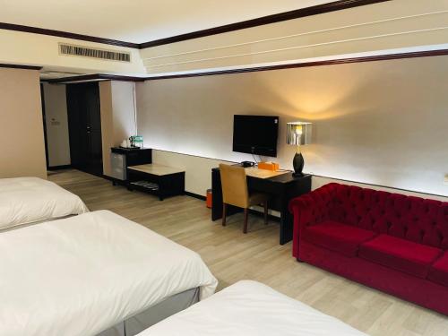 a hotel room with a red couch and a desk at Felicity Business Hotel in Taichung