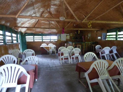 a dining room with white chairs and tables and windows at Rwenzori Turaco View Camp in Kasese