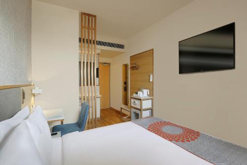 um quarto com uma cama, uma secretária e uma cadeira em Holiday Inn Express Gurugram Sector 50, an IHG Hotel em Gurgaon