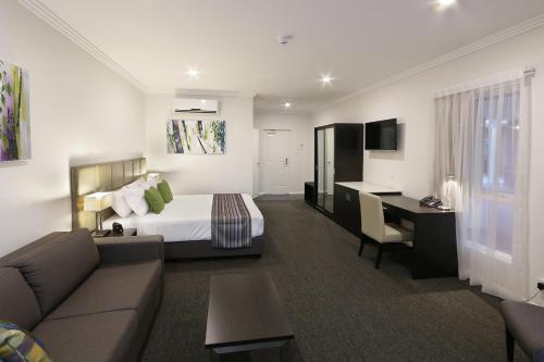 a hotel room with a bed and a couch at Best Western Plus Bolton on the Park in Wagga Wagga