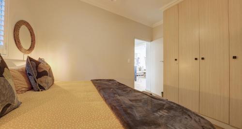 a bedroom with a large bed and a cabinet at Oppiesee Selfcatering Apartments in Herolds Bay