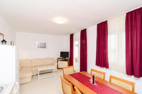 a living room with a dining room table and red curtains at Apartments Feral in Saplunara