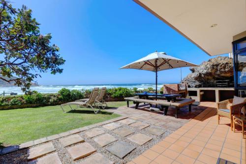 a patio with an umbrella and a table and chairs at Oppiesee Selfcatering Apartments in Herolds Bay