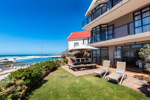 a patio with a table and chairs and the ocean at Oppiesee Selfcatering Apartments in Herolds Bay