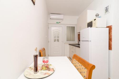 a white kitchen with a table and a refrigerator at Apartments Feral in Saplunara