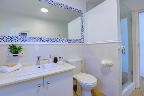 a bathroom with a toilet and a sink and a mirror at Oppiesee Selfcatering Apartments in Herolds Bay