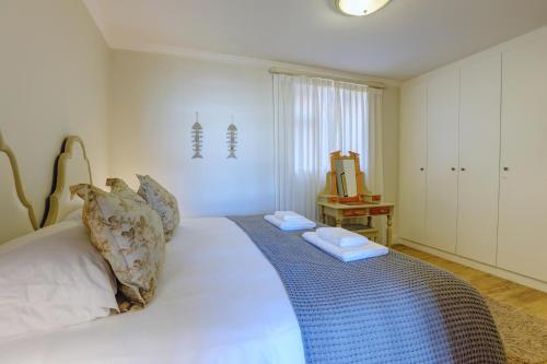 a bedroom with a white bed with two towels on it at Oppiesee Selfcatering Apartments in Herolds Bay