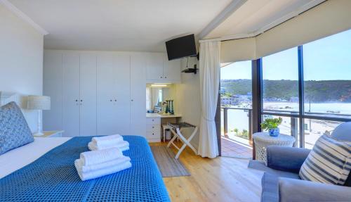 a living room with a blue bed and a large window at Oppiesee Selfcatering Apartments in Herolds Bay