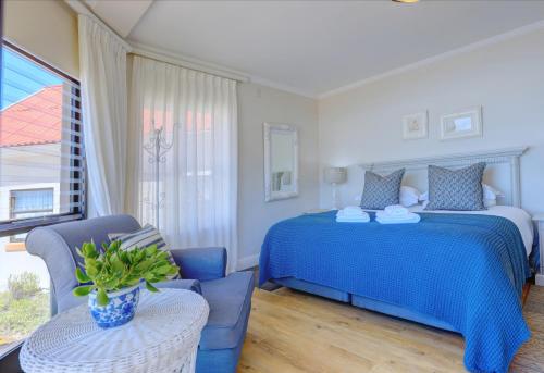 a bedroom with a blue bed and a chair at Oppiesee Selfcatering Apartments in Herolds Bay