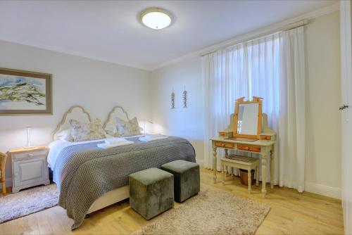 a bedroom with a bed with a mirror and a stool at Oppiesee Selfcatering Apartments in Herolds Bay