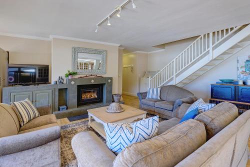 a living room with couches and a fireplace at Oppiesee Selfcatering Apartments in Herolds Bay