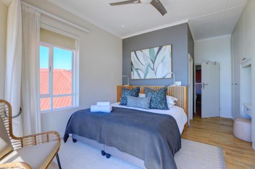 a bedroom with a bed and a chair and a window at Oppiesee Selfcatering Apartments in Herolds Bay