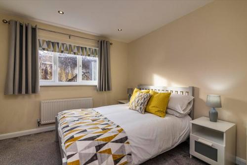una camera da letto con un letto con cuscini gialli e una finestra di Percy House Cosy 2 Bedroom Home, Private Garden FREE PARKING Long Stays welcome a Nottingham