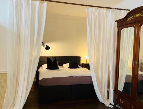 レーゲンスブルクにあるHotel Luxのベッドルーム1室(白いカーテンと鏡付きのベッド1台付)