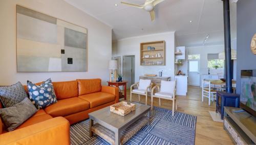 a living room with an orange couch and a table at Oppiesee Selfcatering Apartments in Herolds Bay