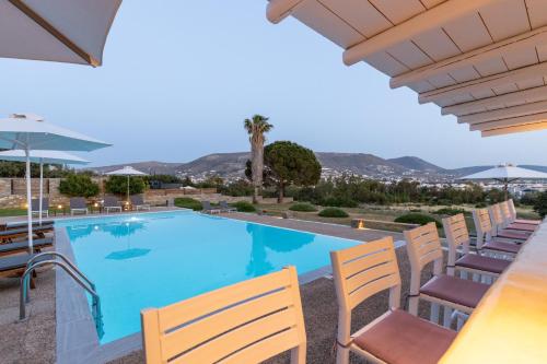 a pool with chairs and umbrellas in a resort at Roses Beach in Parikia