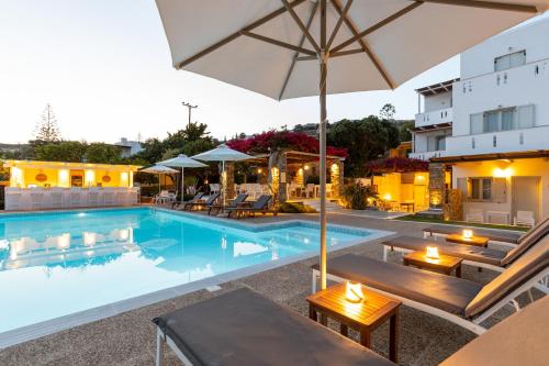 a swimming pool with tables and an umbrella at Roses Beach in Parikia