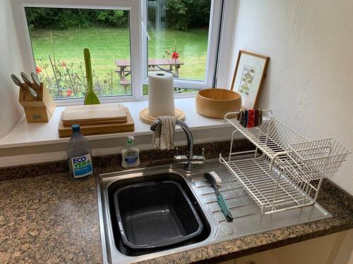 a kitchen sink with a dish drying rack next to a window at Chough Cottage: peace in a gorgeous, rural setting in Helston