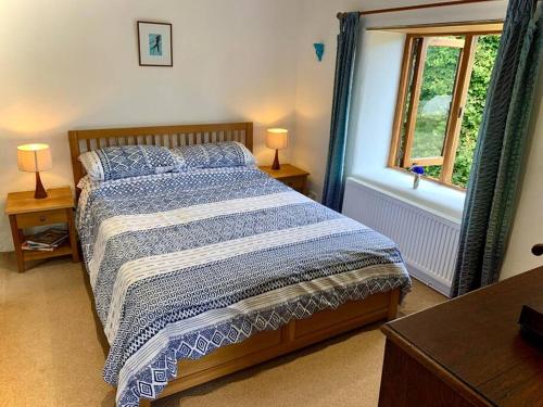 a bedroom with a bed with a blue and white comforter at Chough Cottage: peace in a gorgeous, rural setting in Helston