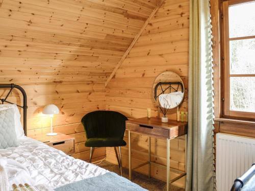 a bedroom with a bed and a desk with a mirror at Forest Lodge Glenisle in Dalbeattie