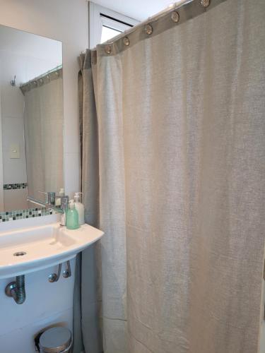 y baño con cortina de ducha y lavamanos. en Los Naranjos en San Salvador de Jujuy