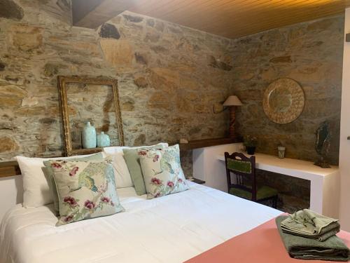 a bedroom with a bed and a stone wall at Casa Da Oliveira in Pedrógão Grande