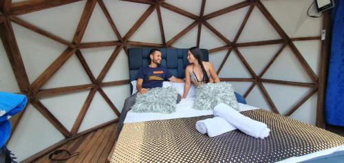 two people sitting on a bed in a yurt at Reserva Ecoturística Villa Diosa in Confines