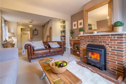 a living room with a brick fireplace and a couch at Immaculate luxury retreat in pretty village with great pubs - Box Valley Cottage in Stoke-by-Nayland
