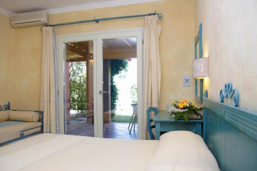 1 dormitorio con cama, escritorio y puerta en TH Costa Rei - Free Beach Resort, en Monte Nai