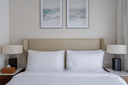 a bedroom with a white bed with two lamps at Alnoon at Address Beach Resort Fujairah in Sharm