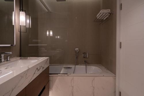 a bathroom with two sinks and a bath tub at Alnoon at Address Beach Resort Fujairah in Sharm