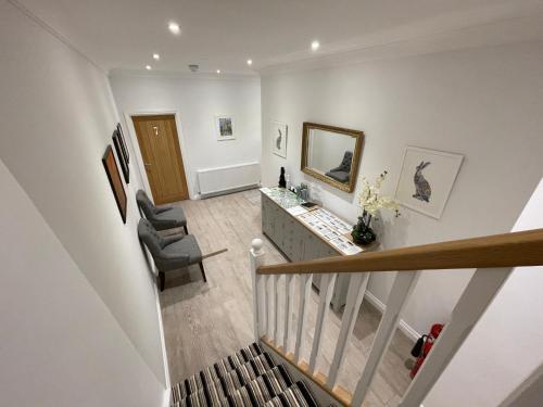 Habitación con escalera con 2 sillas y espejo. en Cotswold Hare en Cirencester