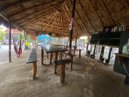 a picnic table and benches in a building with an umbrella at Balam Camping & cabañas in Holbox Island