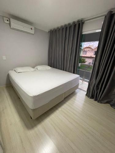1 dormitorio con cama blanca y ventana en Casa para Show Rural Flat Sobrado, en Cascavel