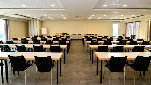an empty lecture hall with tables and chairs at Mezzo Hotel & Business in Beringen