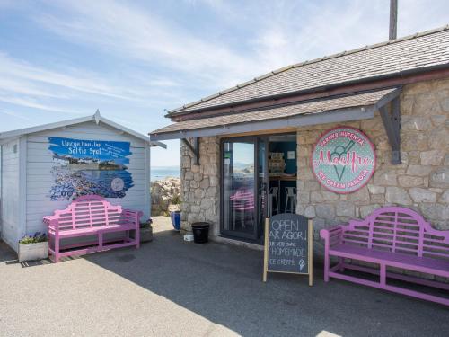 a restaurant with purple benches outside of a building at Brynelian in Moelfre