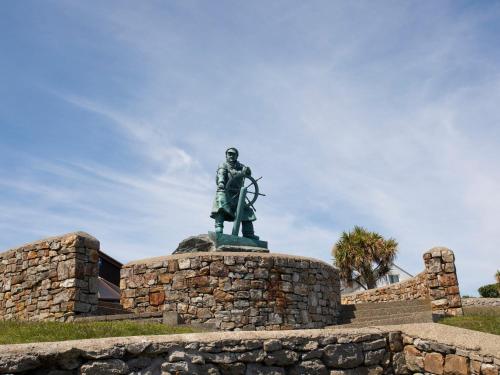 a statue of a man standing on a stone wall at Brynelian in Moelfre