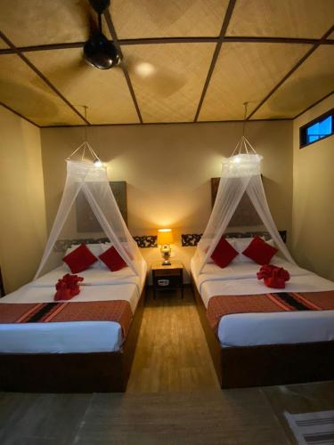 a bedroom with two beds with red pillows at Ombak Dive Resort Perhentian Island in Perhentian Island