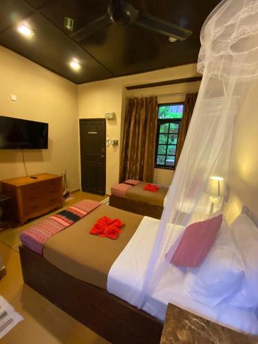 a hotel room with two beds and a television at Ombak Dive Resort Perhentian Island in Perhentian Island