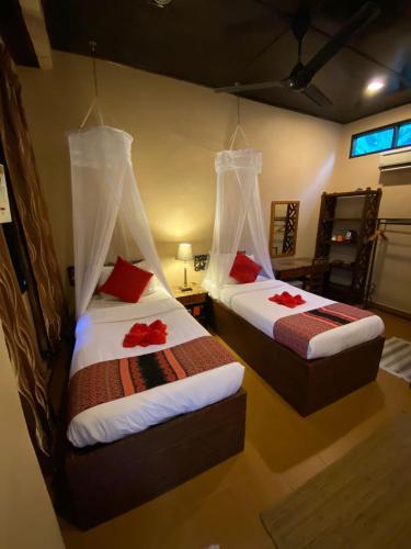 two beds with red pillows in a room at Ombak Dive Resort Perhentian Island in Perhentian Island