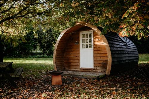 a small wooden cabin with a door in the grass at Caplor Glamping & Lodges in Hereford