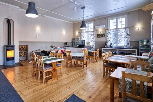 a restaurant with tables and chairs and a fireplace at Hovra Vandrarhem in Korskrogen