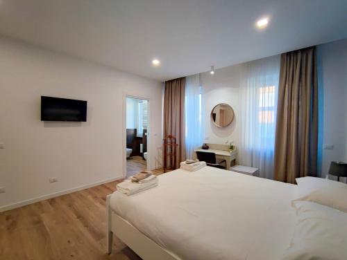 1 dormitorio con 1 cama blanca grande y TV en La residenza del viale, en Treviglio