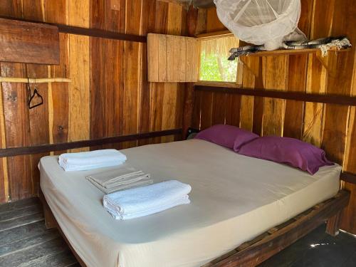 a bed in a wooden room with towels on it at Balam Camping & cabañas in Holbox Island