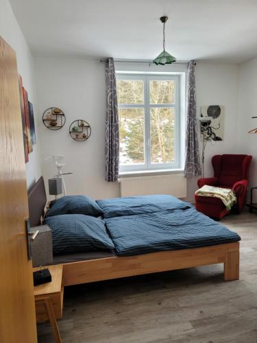 a bedroom with a bed with a blue comforter and a window at Eulennest bis 10 Personen,Wäsche,Reinigung,Parkplatz inklusive,Kurtaxe wird extra berechnet in Altenau